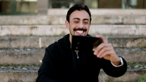 Front-view-of-Arabic-man-having-video-chat-outside,-waving-hand