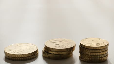 Metal-Euro-coins-arranged-on-white-surface-slow-tilting-over-4K