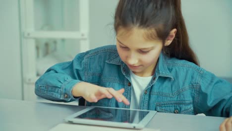 Caucasian-girl-in-jeans-wear-playing-games-on-tablet