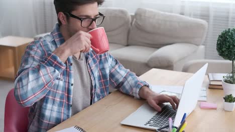 Businessman-drinking-coffee-while-working-on-laptop