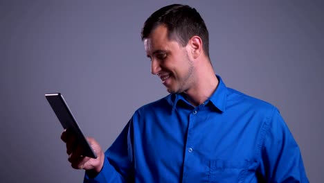 Closeup-portrait-of-adult-positive-caucasian-man-browsing-on-the-tablet-and-smiling-in-front-of-the-camera