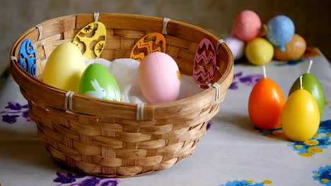 Coloridos-huevos-de-Pascua-verdes,-amarillos-y-rosados-en-una-cesta.-La-mano-masculina-añade-un-huevo-de-Pascua-rosado-y-uno-amarillo.