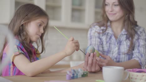 Mama-und-niedliche-kleine-Tochter-Färbung-Ostereier-mit-Farben-und-Pinsel.