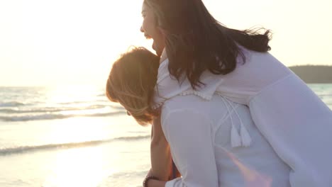 Jóvenes-amigos-LGBT-asiáticos-jugando-en-la-playa,-hermosas-mujeres-amigas-se-sienten-felices-y-divertidas-relajarse-jugando-en-la-playa-cerca-del-atardecer-en-el-mar-en-la-noche.-Lifestyle-amistad-lesbiana-viaje-en-la-playa.-Disparo-a-cámara-lenta.