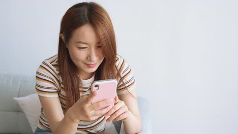 Asian-woman-using-cellphone-in-living-room