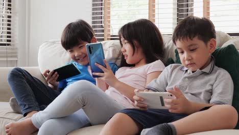 Group-of-children-friend-using-smartphone-to-play-game-together-at-home.-Children-playing-game-with-happy-emotion.