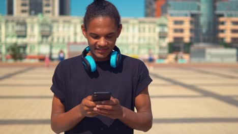 fröhlicher-junger-Mann-mit-App-auf-Smartphone-zu-Fuß-auf-der-Straße