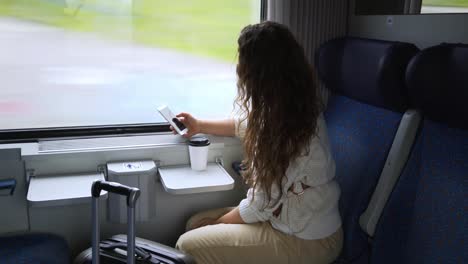 Viajar-en-la-mujer-del-tren-con-teléfono-cerca-de-la-ventana