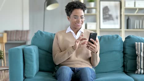 Das-fröhliche-Mädchen-mit-Telefon,-während-auf-der-Couch-sitzen