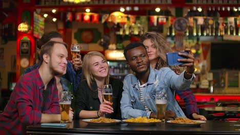 In-der-Bar-oder-im-Restaurant-nimmt-hispanic-man-Selfie-von-sich-und-ihren-besten-Freunden.-Gruppe-Schöne-junge-Menschen-in-stilvollen-Establishment