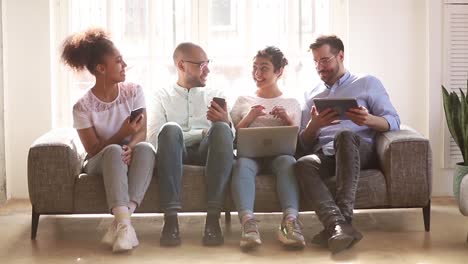 Jóvenes-estudiantes-multiculturales-riendo-hablando-divirtiéndose-con-tecnología-digital