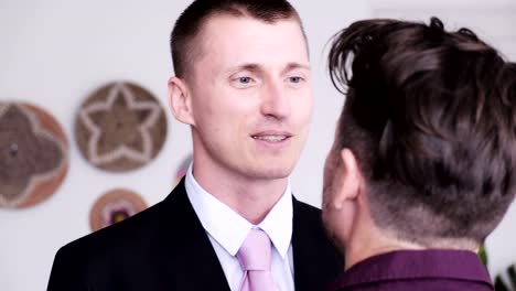 Gay-man-help-his-partner-putting-on-tie-for-job-interview.-Kissing-good-bye.