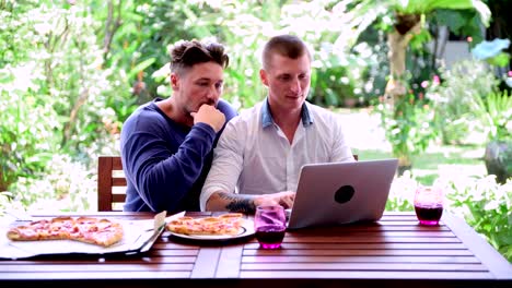 Gay-couple-having-pizza-for-lunch.-Drinking-wine.