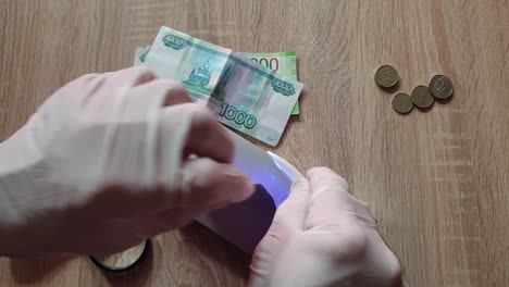 Überprüfung-von-Banknoten-durch-eine-UV-Lampe-auf-Echtheit.