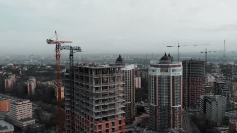 Group-of-caucasian-workers-in-orange-helmets-working-on-roof-of-unfinished-building.-Workers-at-construction-of-high-rise-residential-complex