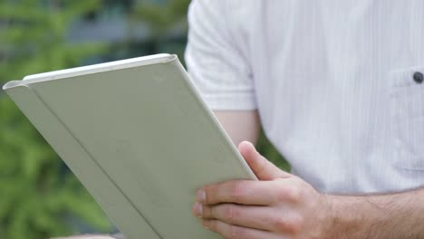 Man-touching-screen-on-modern-digital-tablet-pc-outdoors