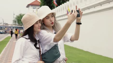 Happy-Asian-lesbian-couples-selfie-video-chat-with-friends-enjoying-traveling-in-Thailand.-Beautiful-young-women-having-fun-in-vacation-time.-LGBT-concept.