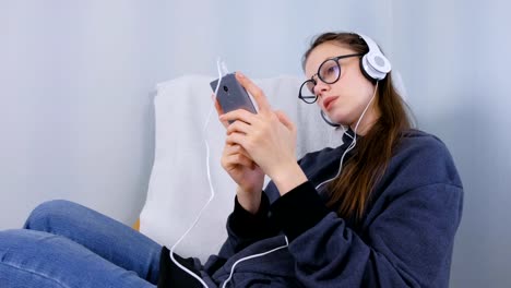 Woman-listens-music-in-headphones-on-smartphone-and-sings-a-song.