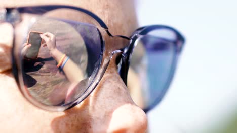 Teléfono-móvil.-Una-mujer-con-gafas-de-sol-mira-un-teléfono-móvil.