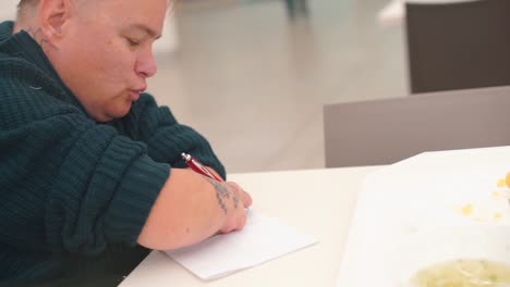 Disabled-woman-writes-pen-text-on-paper-at-the-table