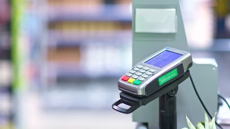 Primer-plano,-terminal-de-pago-en-un-supermercado,-pago-sin-contacto-para-compras,-nfc.-La-mano-de-la-mujer-lleva-el-teléfono-al-reno-para-el-pago.-4k,-ProRes