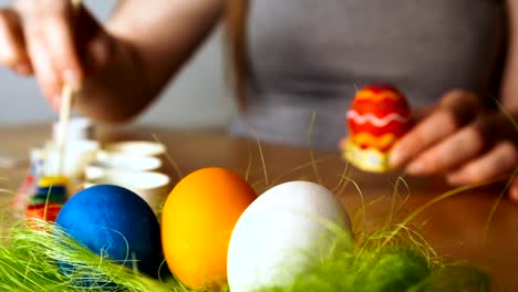 Una-joven-mujer-pinta-huevos-de-Pascua-con-un-cepillo-en-el-fondo-de-la-mesa-de-madera