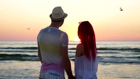 Young-beautiful-couple-watching-an-amazing-sunset-and-kissing-on-beach