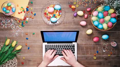 Man-using-laptop-computer-on-table-decorated-with-easter-eggs-Top-view