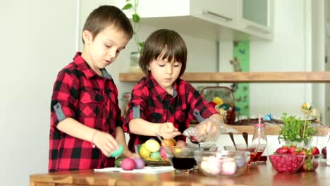 Two-children,-boys,-coloring-easter-eggs-at-home,-eating-strawberries