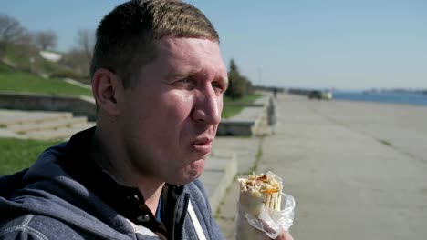 Disabled-man-in-wheelchair-eats-doner-kebab/shawarma.-Man-with-spinal-column-disease