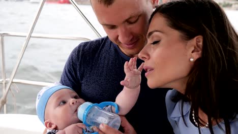 dad-feeds-child-water-from-bottle,-family-together-with-baby-on-vacation,-parents-and-little-boy-with-bottle-on-sea,-mom,-dad