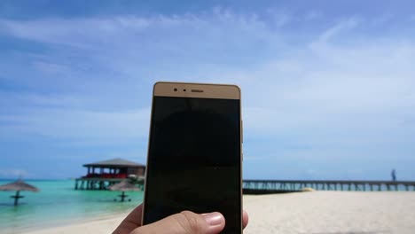 POV-shot-of-a-smart-phone-taking-photo-in-tourist-hand.-Having-fun-at-ocean-vacation