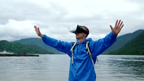 A-man-uses-virtual-reality-glasses-on-the-background-of-a-mountain-lake