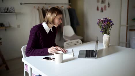 Mujer-joven-sentada-en-la-mesa-y-escribiendo-en-cuaderno-de-teclado.-Mujer-de-negocios