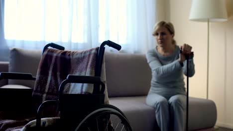 Sad-retired-lady-waiting-for-husband-at-hospital,-looking-at-wheelchair,-rehab