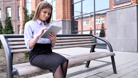 Mujer-sentada-al-aire-libre-navegación-Internet-en-Tablet