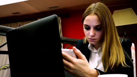 Business-Girl-in-cafe-with-laptop-and-smartphone-looking-for-information-on-the-Internet-on-your-phone