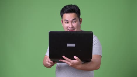 Young-handsome-overweight-Asian-man-against-green-background