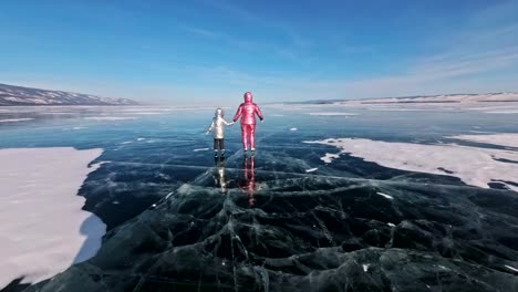 La-familia-es-hielo-en-el-día.-Chicas-a-montar-en-patines-de-hielo-figura-en-la-naturaleza.-Madre-e-hija-cabalgando-juntos-sobre-hielo-en-las-grietas.-Diversión-de-invierno-al-aire-libre-para-clima-agradable-deportista.