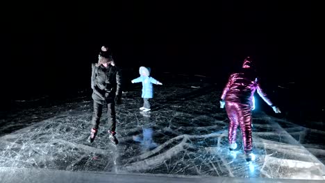 La-familia-es-noche-de-patinaje-sobre-hielo.-Niñas-y-niños-a-montar-en-patines-de-hielo-figura-en-la-naturaleza.-Madre,-hija-e-hijo-a-caballo-juntos-en-el-hielo-en-las-grietas.-Diversión-de-invierno-al-aire-libre-para-clima-agradable-deportista.