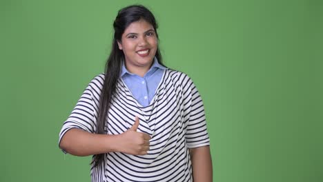 Young-overweight-beautiful-Indian-businesswoman-against-green-background