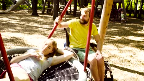 Woman-is-lying-on-a-swing-and-a-man-is-pushing-a-swing