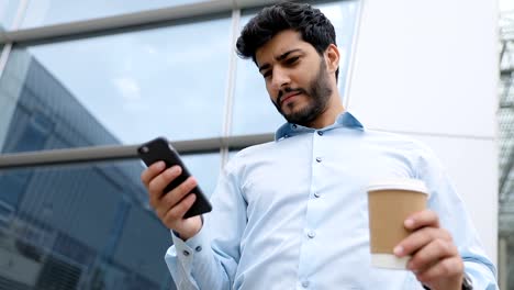 Hombre-de-negocios-con-teléfono-y-café-cerca-de-oficina-de-negocios