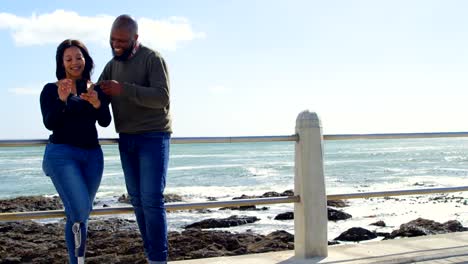 Pareja-feliz-con-teléfono-móvil-junto-a-la-barandilla-en-un-día-soleado-4k