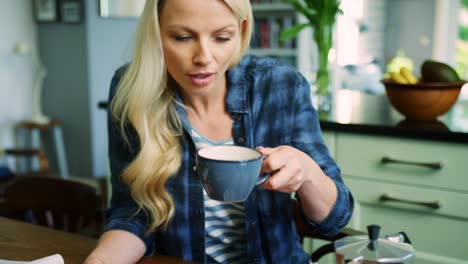 Schöne-blonde-Frau-Überprüfung-Smartphone-beim-Kaffeetrinken