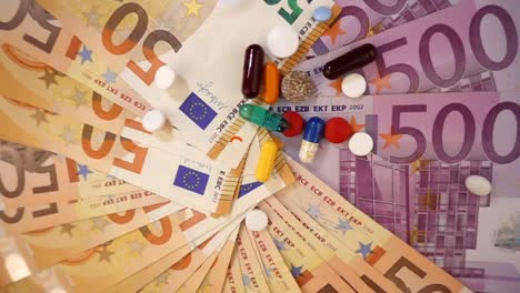 VIDEO,-various-pharmaceutical-drugs-falling-on-euro-banknotes-rotating-below-on-slow-motion