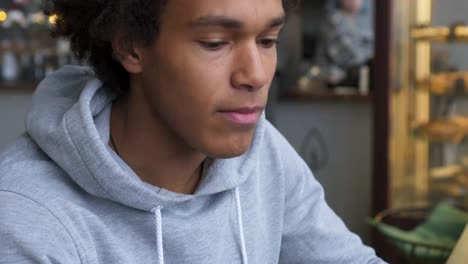 Man-drinking-coffee-and-using-mobile-phone-in-cafe