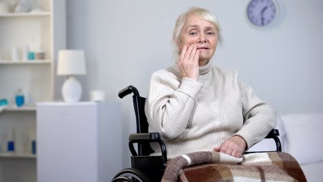 Desperate-lady-in-wheelchair-wiping-tears-and-looking-into-camera,-depression