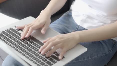 Closeup-hand-of-freelance-woman-working-and-typing-on-laptop-computer-sitting-on-couch-at-living-room,-girl-on-sofa-using-notebook-checking-email-or-social-network,-business-and-lifestyle-concept.