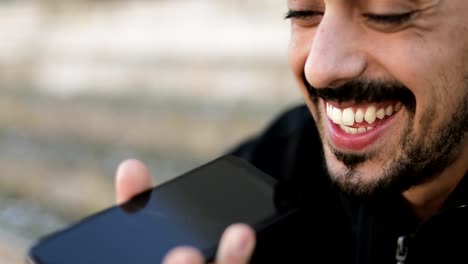 Closeup-of-young-mans-face-talking-on-phone-with-speakerphone